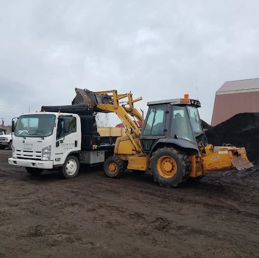 Jesstone & Sons dump truck and backhoe loading mulch at the Erie yard